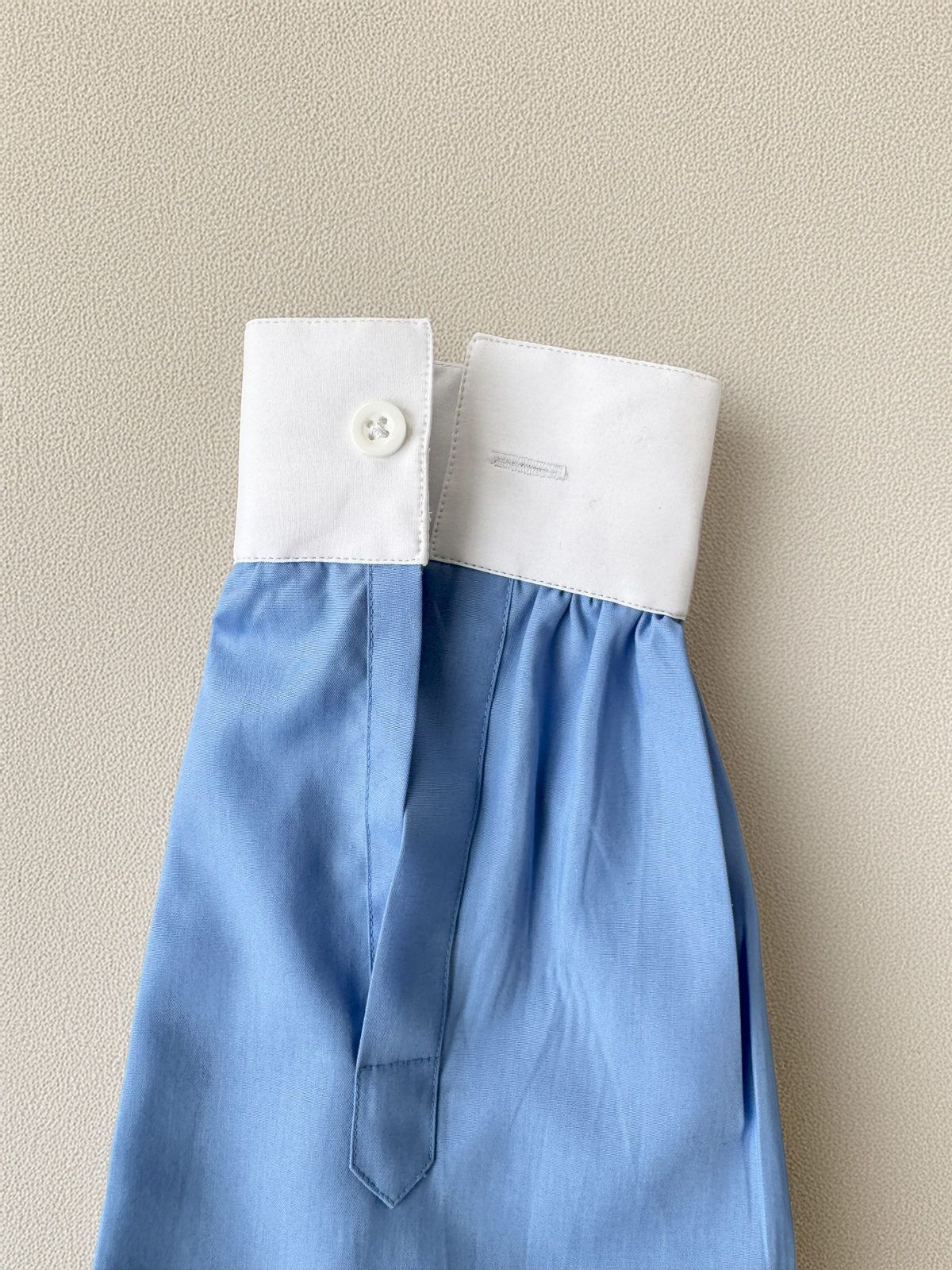 Blue and white dress with a button on a beige background