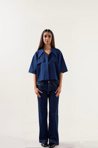 Woman wearing a blue shirt and dark jeans on a white background
