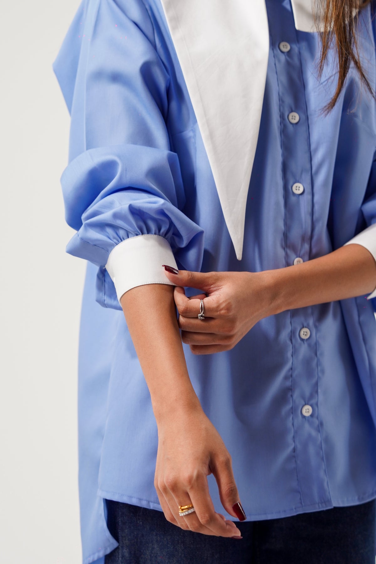 Person wearing a light blue shirt with rolled-up sleeves on a plain background, ishq e amore miss management top 