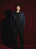 Person wearing a navy blue linen jacket and pants against a red curtain background ishq e amore for him 